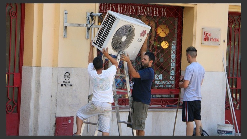 El gran aliado del verano. Dos jóvenes instalan un aire acondicionado en un local del centro.  (Rosario3.com)