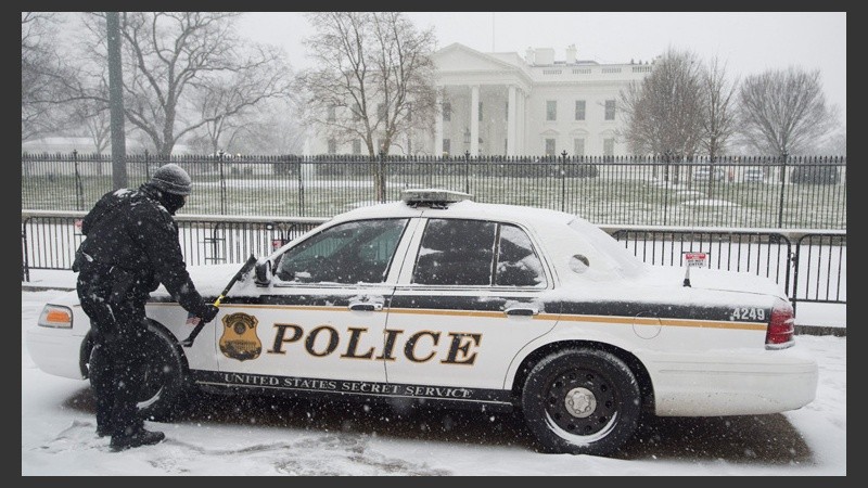 Un policía limpia su auto. Detrás, la Casa Blanca. (EFE)