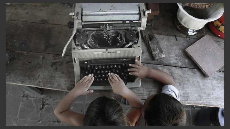 Dos chicos que viven en la isla se entretienen con una máquina de escribir en el patio de la escuela. (Alan Monzón/Rosario3.com)