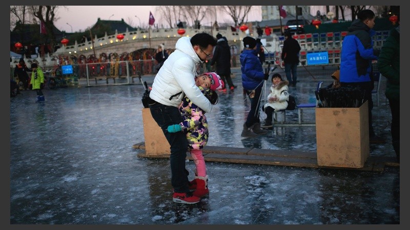 Grandes y chicos disfrutan del lago totalmente helado en el centro de Pekín. (EFE)