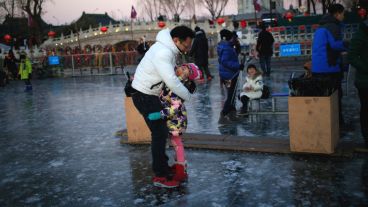 Grandes y chicos disfrutan del lago totalmente helado en el centro de Pekín. (EFE)