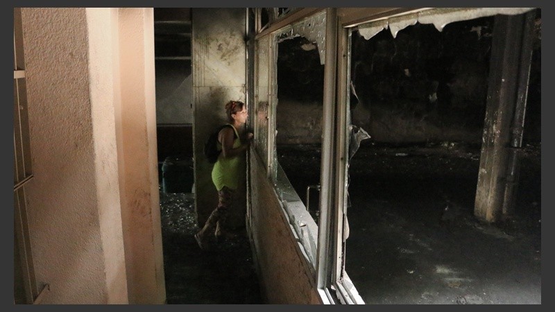 Una mujer mira el interior de la cochera incendiada.