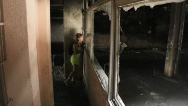 Una mujer mira el interior de la cochera incendiada.