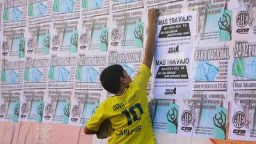 Un joven sobre unos afiches pegados anunciando la medida de protesta. (Alan Monzón/Rosario3.com)