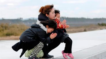 Una mujer y sus hijos rezan en memoria de las víctimas del terremoto y posterior tsunami de hace cinco años en Arahama en Sendai.