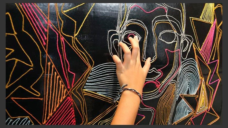 Una joven interacciona con un cuadro expuesto en la muestra 