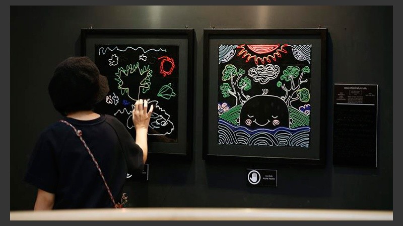 Una joven interacciona con un cuadro expuesto en la muestra 