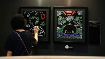 Una joven interacciona con un cuadro expuesto en la muestra "Por Favor Toque" en el Centro de Arte y Cultura de Bangkok.