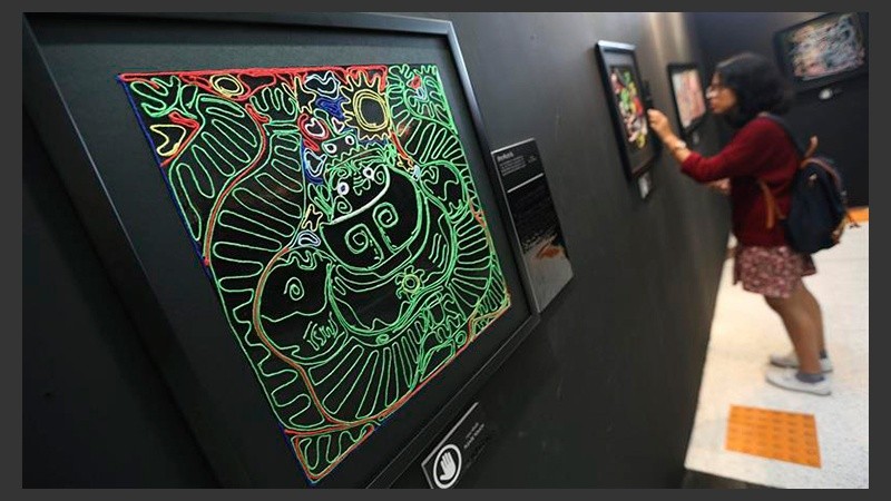 Una joven interacciona con un cuadro expuesto en la muestra 