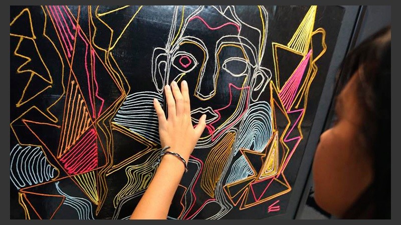 Una joven interacciona con un cuadro expuesto en la muestra 