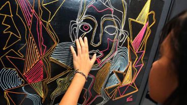 Una joven interacciona con un cuadro expuesto en la muestra "Por Favor Toque" en el Centro de Arte y Cultura de Bangkok.