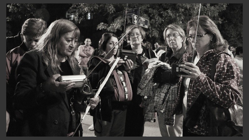Mujeres sintonizando Radio 2 para oír las palabras del padre Ignacio durante la procesión. (Alan Monzón/Rosario3.com)