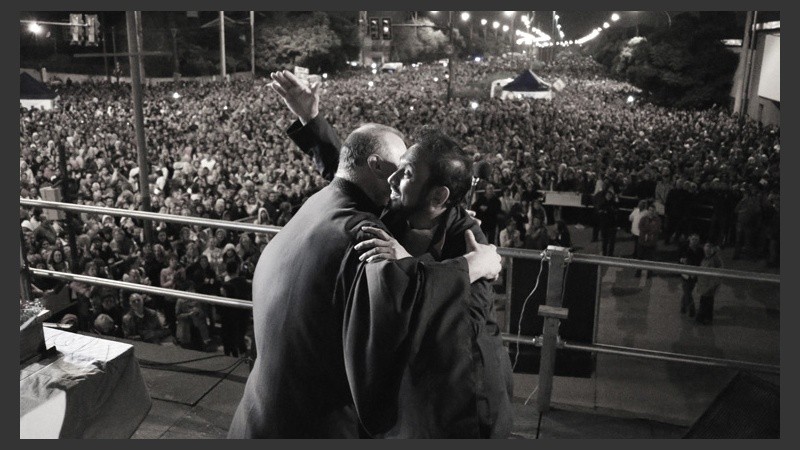 Ignacio saluda con una sonrisa a otro cura en el escenario ante la multitud. (Alan Monzón/Rosario3.com)