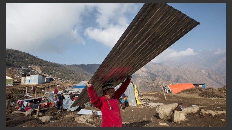 Una joven damnificada carga con una plancha metálica para colocarla sobre el tejado de su casa tras una de las entrega de materiales. (EFE)
