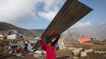 Una joven damnificada carga con una plancha metálica para colocarla sobre el tejado de su casa tras una de las entrega de materiales. (EFE)
