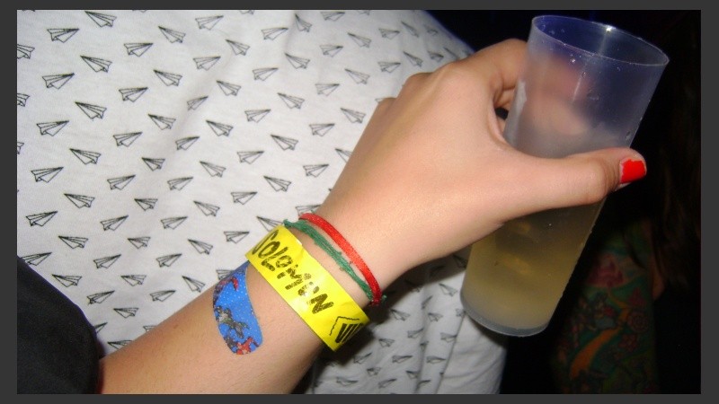 En la muñeca de una joven, la pulserita del vip y en tono de broma, una bandita de Superman. 