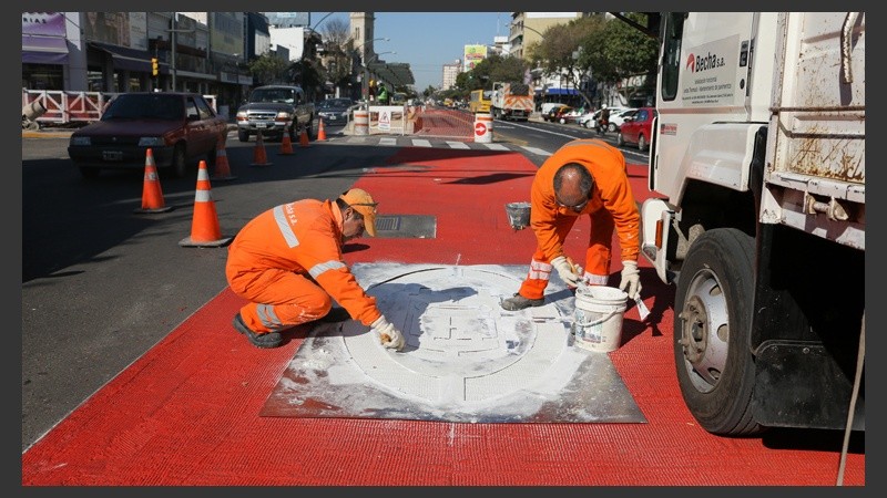 Dos obreros trabajan en la pintura para señalizar uno de los carriles. (Rosario3.com)