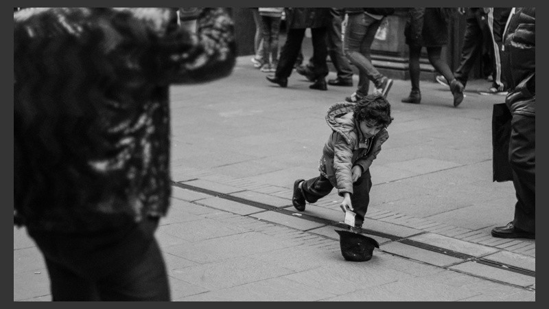 Un niño deja un billete de 10 pesos dentro de la gorra del artista. (Alan Monzón/Rosario3.com)