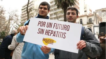 Dos jóvenes posan con el cartel que invita a la gente a vacunarse.