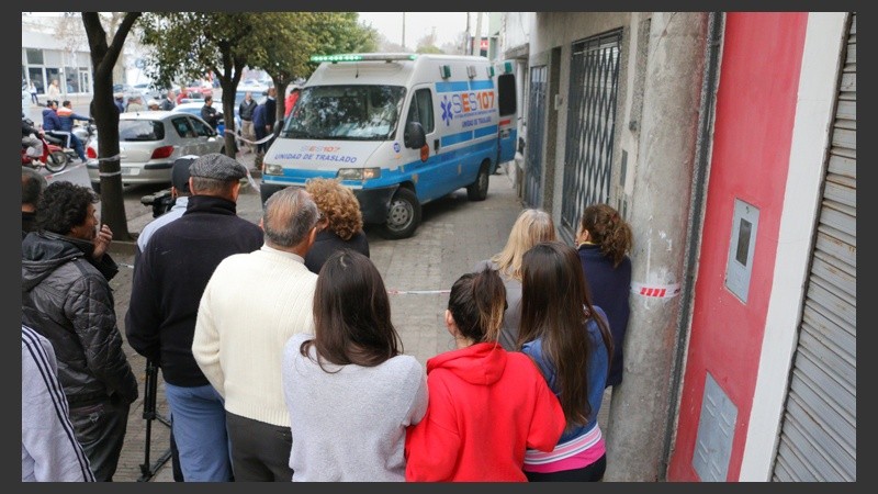 Una ambulancia del SIES para retirar el cuerpo mientras vecinos observan. 