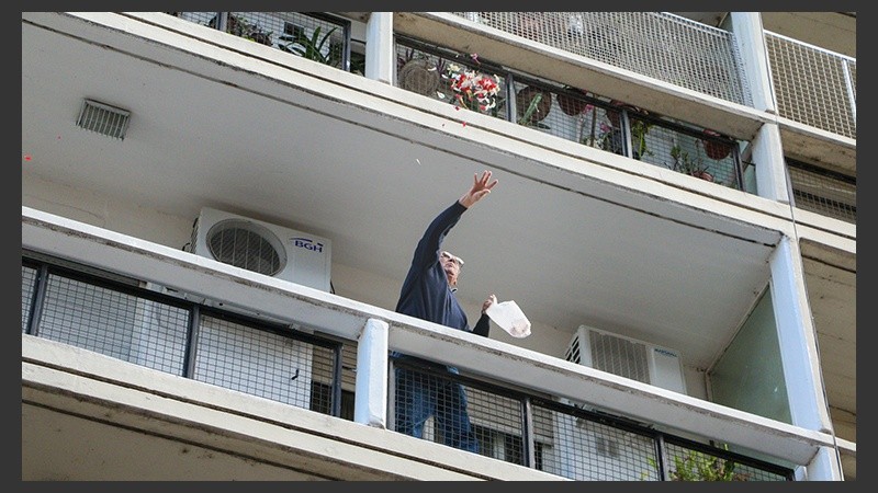 Un señor arroja desde su balcón flores durante el paso de la Virgen. (Alan Monzón/Rosario3.com)