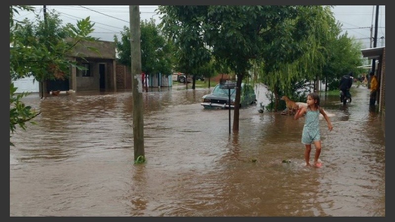Una nena camina por una vereda transformada en río, en Arroyo Seco.