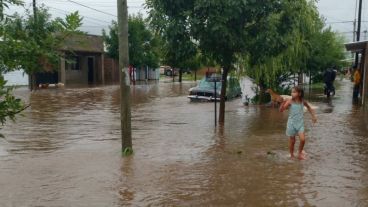 Una nena camina por una vereda transformada en río, en Arroyo Seco.