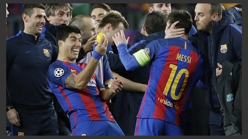 Suárez le muestra el amuleto a Messi. 
