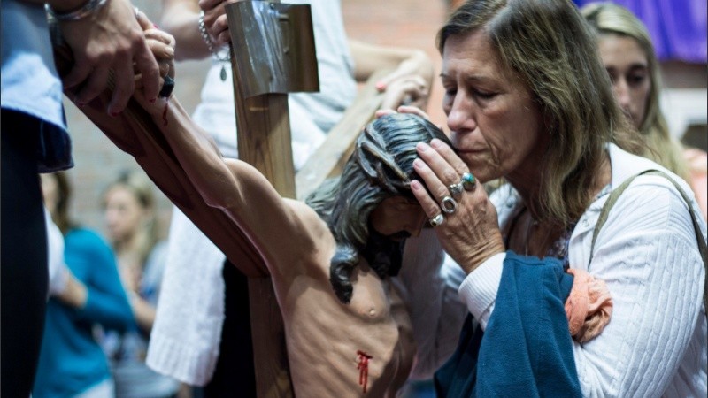 Una mujer besa la cabeza del cristo crucificado dentro de la parroquia del Padre Ignacio