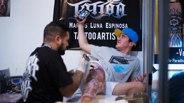 Un joven transmite en vivo con su celular mientras lo tatúan en el primer día del encuentro. (Alan Monzón/Rosario3.com)