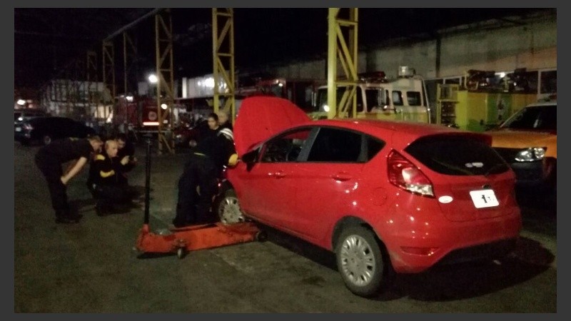 Bomberos trabajando en el auto, que levantaron con un gato (hidráulico). 