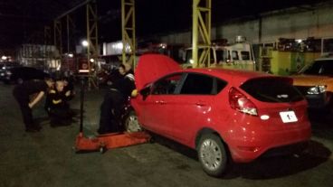 Bomberos trabajando en el auto, que levantaron con un gato (hidráulico).