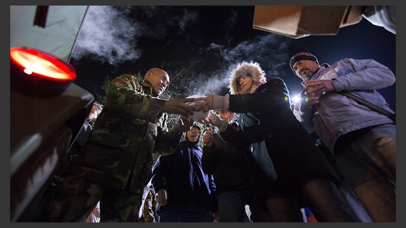 Personas se acercan en busca de un plato de comida.