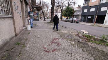 El lugar exacto del crimen y la mancha de sangre en la vereda.