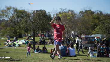 Un joven sonríe tras remontar su barrilete este domingo en el parque.