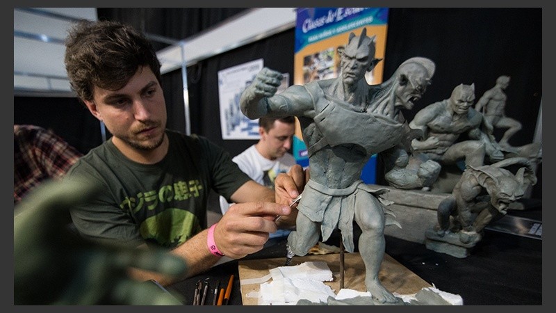 Jóvenes con esculturas de personajes de historietas. Los visitantes puden ver cómo trabajan.