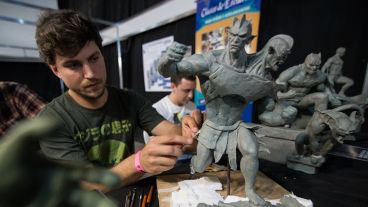 Jóvenes con esculturas de personajes de historietas. Los visitantes puden ver cómo trabajan.