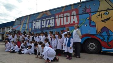 Los chicos de escuelas y docentes posan frente al micro ploteado con los colores de la FM VIDA.
