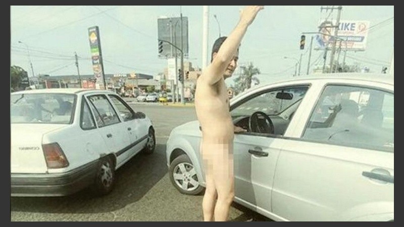 El policía, desnudo, al lado de su auto.