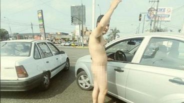El policía, desnudo, al lado de su auto.