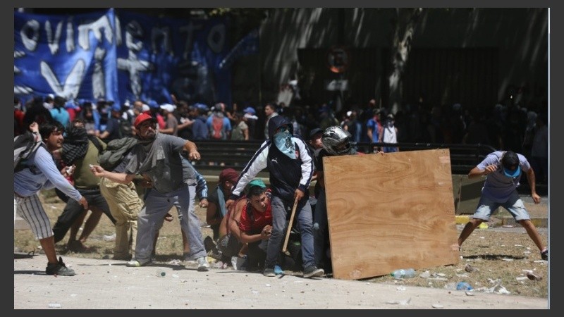 Grupos de manifestantes arrojan todo tipo de proyectiles contra el escudo policial.