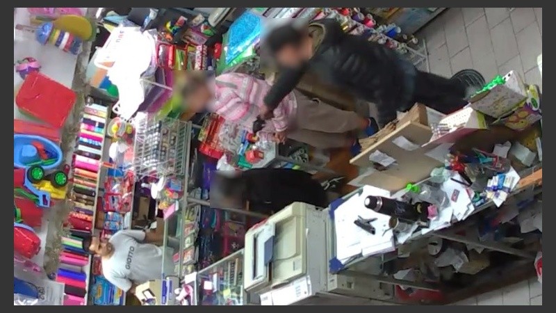 Las cámaras registraron cómo el delincuente apunta con su arma a los clientes y el dueño.
