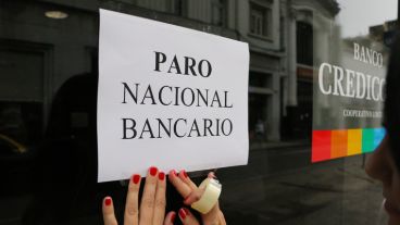 Una empleada pega un cartel en un entidad bancaria. (Alan Monzón/Rosario3.com)