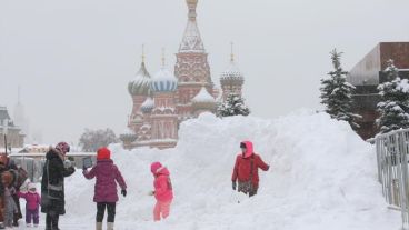 Un grupo de chicos juegan con nieve frente a la Catedral San Basilio de Moscú.
