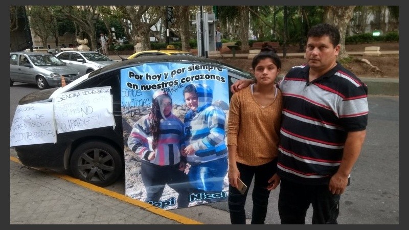 Los padres de Florencia y Melanie Aranda con los carteles y pedidos en su auto.