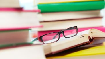 Close-up image of eyeglasses among piles of books