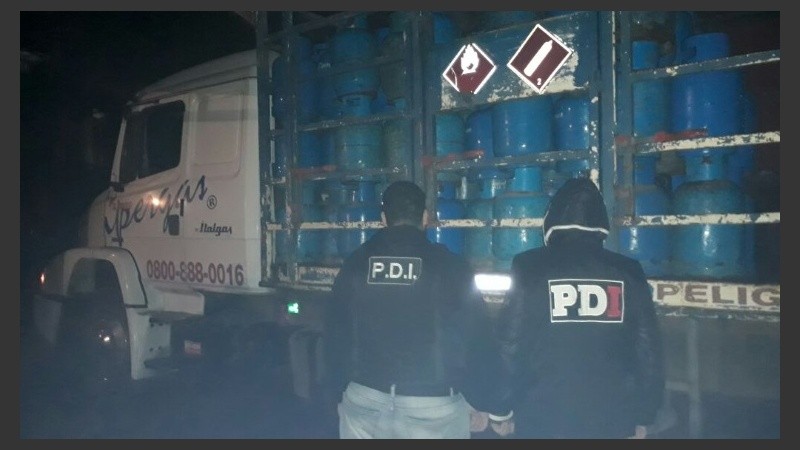 Oficiales de PDI con las garrafas secuestradas. 