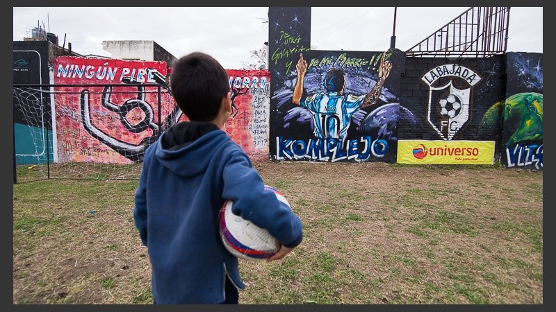 Un niño mira una pintura en el campito donde Messi jugó desde chiquito en la esquina de su casa.
