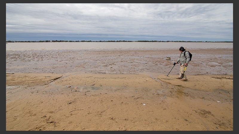 Un hombre con su detector de metales aprovecha la bajante para buscar objetos de su interés.