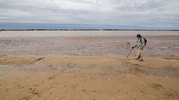 Un hombre con su detector de metales aprovecha la bajante para buscar objetos de su interés.